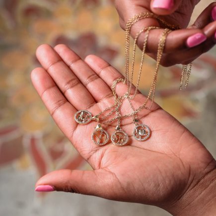 Zodiac Necklace being held by model displaying different Zodiac signs 